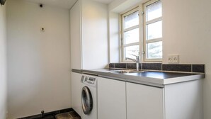 Ein kleiner Waschraum mit Waschmaschine, Spüle und einem Fenster, das für natürliches Licht sorgt.