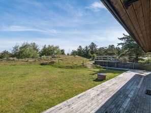 Una terraza de madera con una mesa de picnic y un brasero.