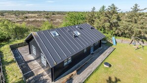 Eine Holzhütte mit geneigtem Dach, zwei Dachfenstern und einer Terrasse.