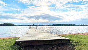 A wooden pier extending into a calm lake with a clear sky above.