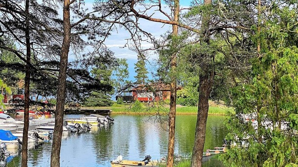 A serene lakeside view with boats docked, surrounded by trees and a small building in the background.