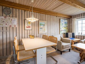 A room with a wooden ceiling, a white table, wicker chairs, a clock, framed artwork, and a window with curtains. - 4 Person Holiday Home in Norre Nebel (Norre Nebel)