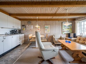 Una cocina moderna con armarios blancos, un comedor con mesa y sillas de madera, y un amplio ventanal con una obra de arte.