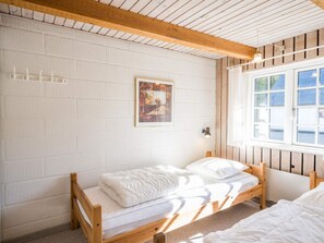 Una habitación con cama, ventana y lámpara de pared.