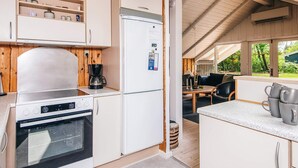 A compact kitchen with white cabinetry, a built-in oven, a coffee maker, and a refrigerator. - 4 Person Holiday Home in Norre Nebel (Norre Nebel)