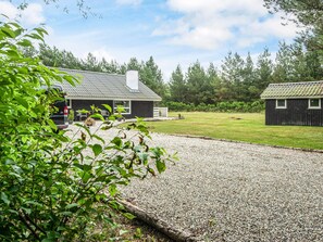 A gravel driveway leading to a black building with a white fence and a smaller structure nearby. - 4 Star Holiday Home in Norre Nebel (Norre Nebel)
