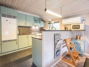 A kitchen with a central island, a refrigerator, a stove, and a microwave. - 4 Star Holiday Home in Norre Nebel (Norre Nebel)