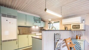 A compact kitchen with a central island, a refrigerator, a microwave, and a stove. - 4 Star Holiday Home in Norre Nebel (Norre Nebel)