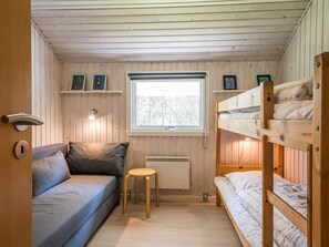 A compact room with a bunk bed, a sofa, a small stool, and a window with a view of trees. - 4 Star Holiday Home in Norre Nebel (Norre Nebel)