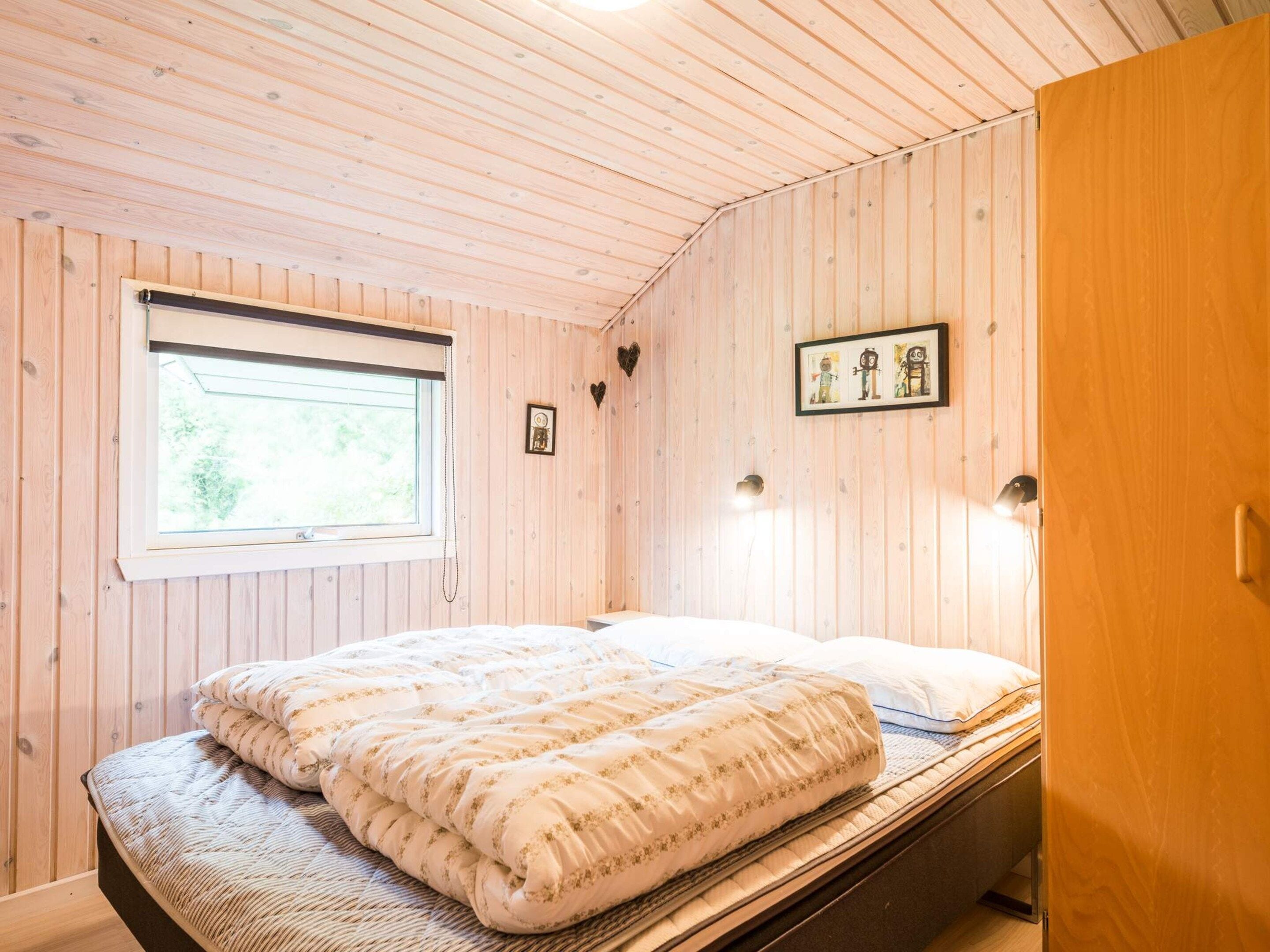 A room with a bed, a window, and wooden walls.