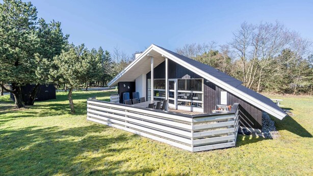 A modern, single-story house with a sloped roof, large windows, and a wooden deck. - 4 Star Holiday Home in Norre Nebel (Norre Nebel)