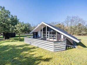 A modern, single-story house with a sloped roof, large windows, and a wooden deck. - 4 Star Holiday Home in Norre Nebel (Norre Nebel)