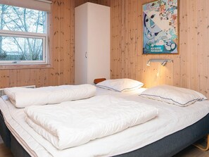Een slaapkamer met twee bedden, houten wanden, een raam en een poster aan de muur.