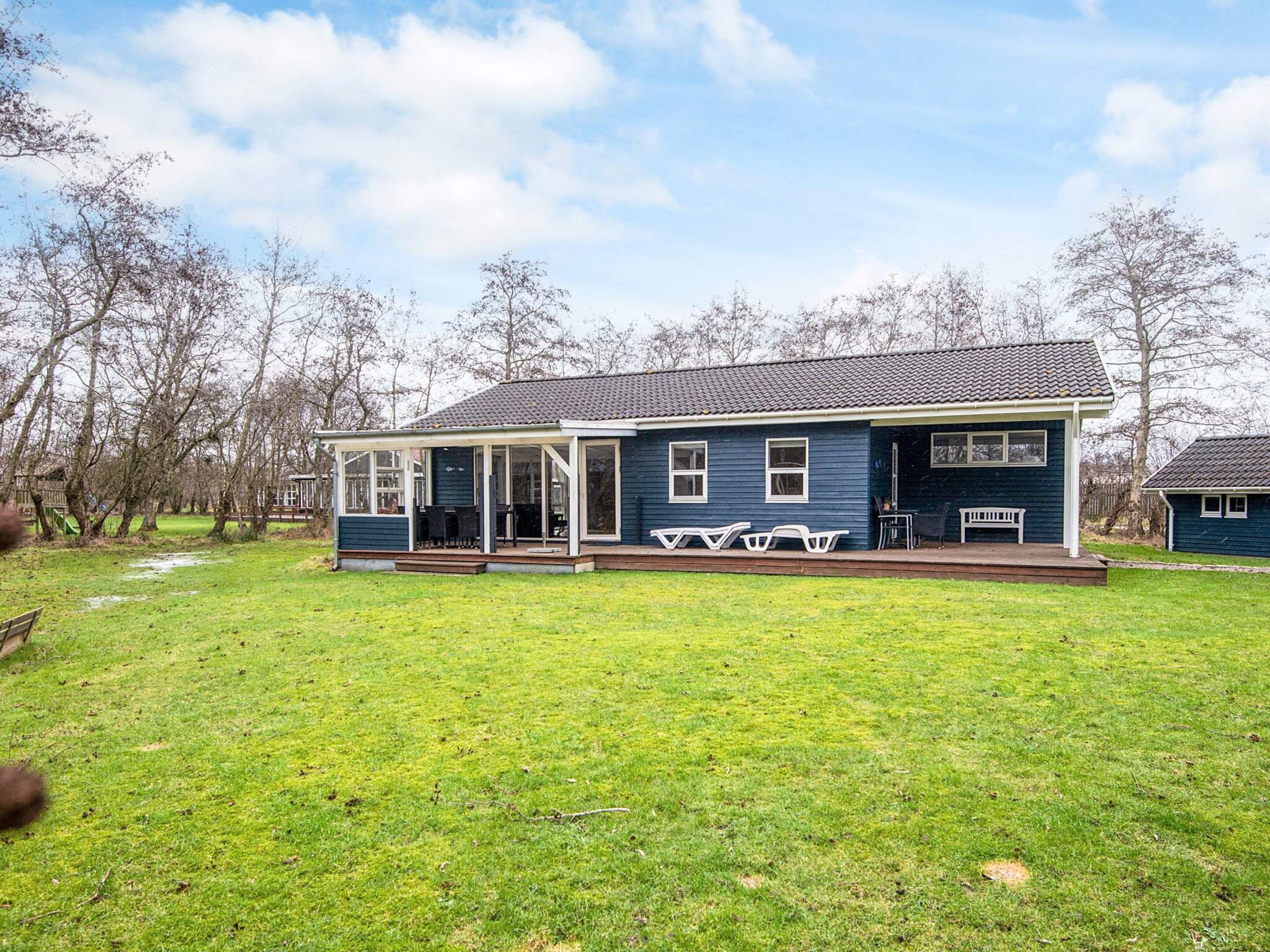 A single-story house with a covered porch, a small deck, and a grassy yard.