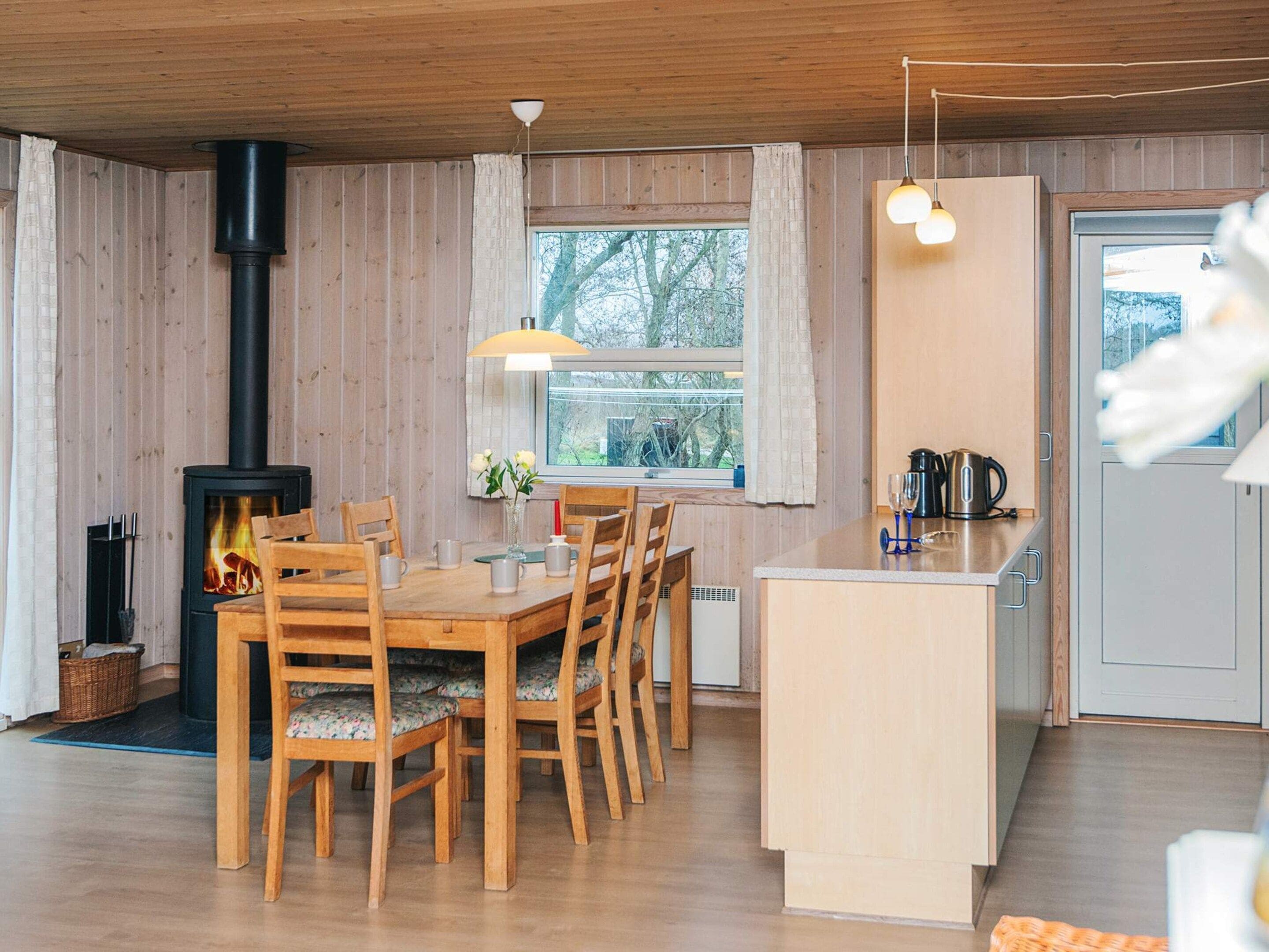 Interior acogedor de una cabaña con comedor, cocina y chimenea.