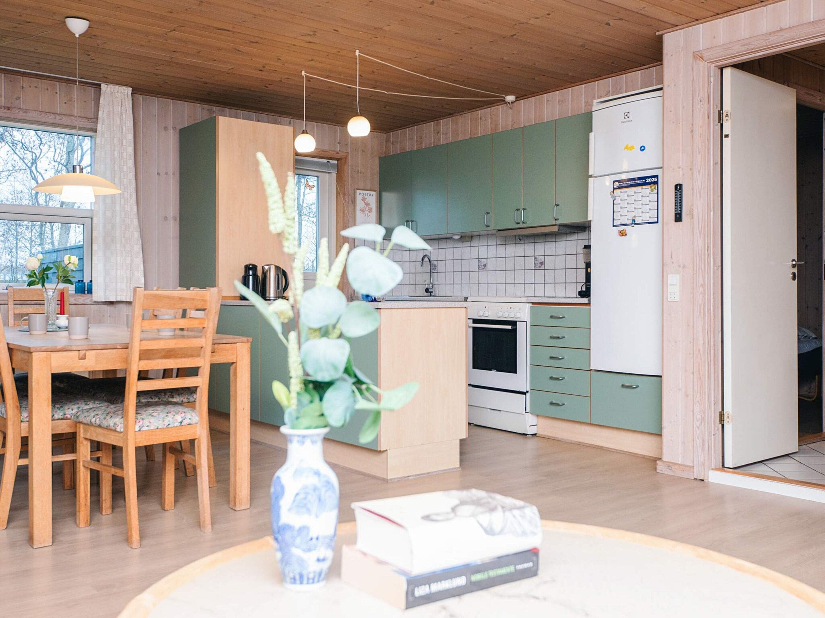 A modern kitchen with wooden cabinets, a white refrigerator, and a dining area with a wooden table and chairs.