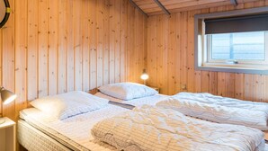 A wooden-paneled room with two beds, a window, and a nightstand with a lamp. - 4 Person Holiday Home in Henne (Henne)