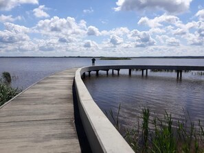 A wooden boardwalk extending over water, with a person standing at the end. - 4 Person Holiday Home in Henne (Henne)