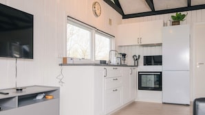Une cuisine moderne avec des meubles blancs, un four encastré, un réfrigérateur et une fenêtre au-dessus de l’évier.