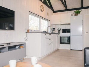 Eine moderne Küche mit weißen Schränken, einem Einbauofen, einem Kühlschrank und einem Fenster über der Spüle.