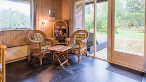 A cozy room with wicker furniture, a bookshelf, and a view of the outdoors. - 6 Person Holiday Home in Henne (Henne)