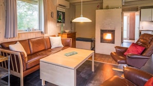 A cozy living room with a fireplace, leather sofas, a coffee table, and a dining area. - 6 Person Holiday Home in Henne (Henne)