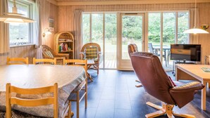 A wooden interior with a dining table, chairs, a leather sofa, a television, and a bookshelf. - 6 Person Holiday Home in Henne (Henne)