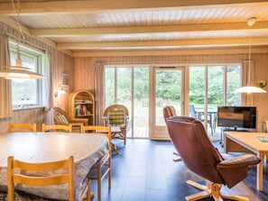Un interior de madera con una mesa de comedor, sillas, un sofá de cuero, un televisor y una estantería.