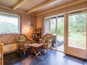 A cozy room with wicker furniture, a bookshelf, and a large sliding glass door leading to an outdoor area. - 6 Person Holiday Home in Henne (Henne)