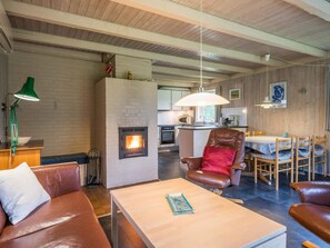 A cozy living room with a fireplace, leather furniture, and a dining area with wooden chairs. - 6 Person Holiday Home in Henne (Henne)