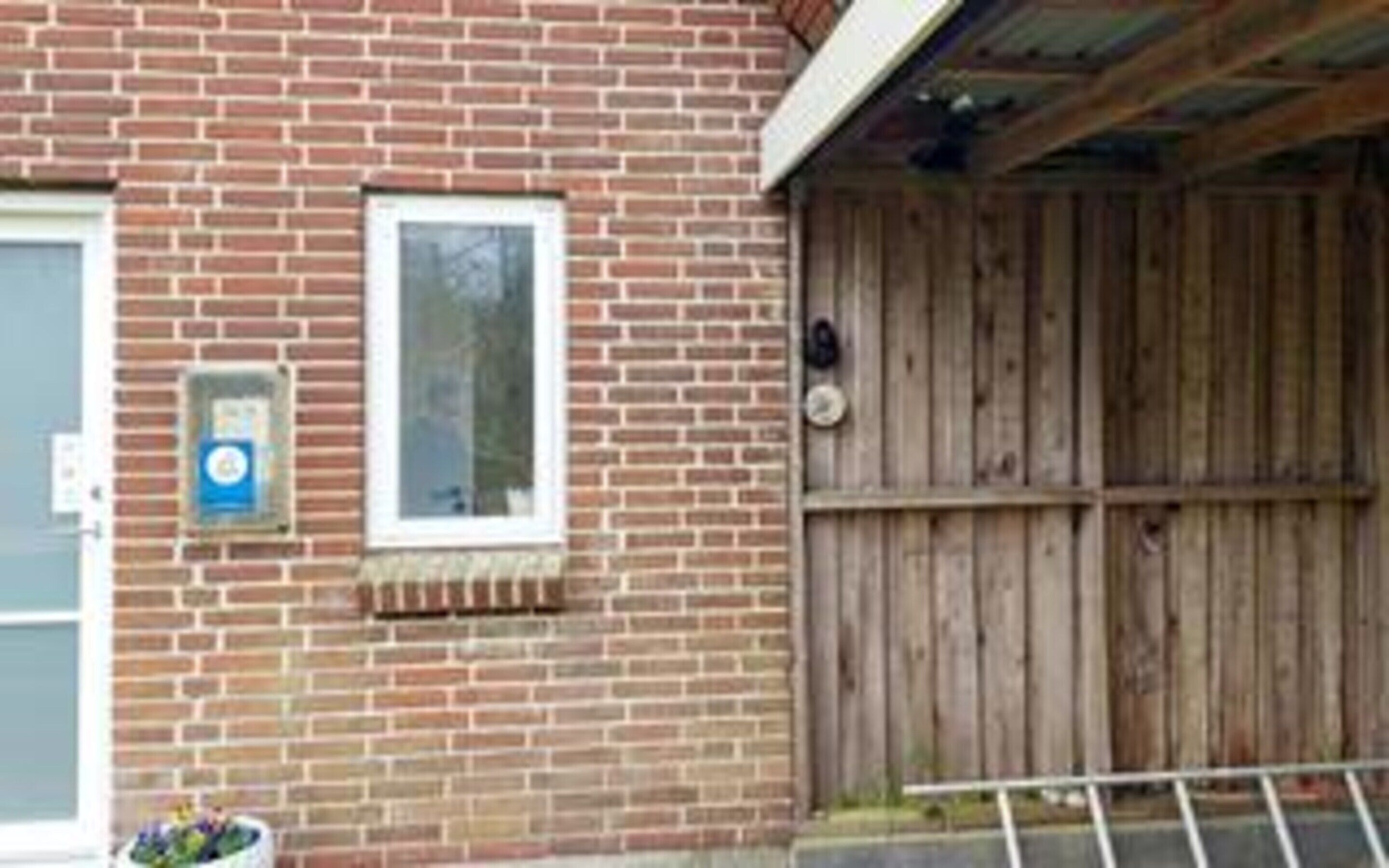 Ein Backsteinhaus mit Holzzaun, Fenster und Briefkasten.