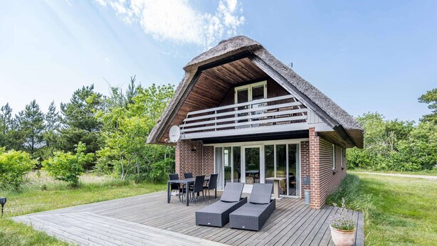 A two-story house with a thatched roof, a balcony, and a wooden deck. - 6 Person Holiday Home in Henne (Henne)