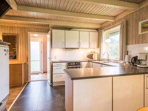 A modern kitchen with white cabinets, a built-in oven, a microwave, and a coffee maker. - 6 Person Holiday Home in Henne (Henne)