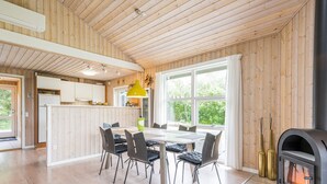 Une cuisine moderne avec un lambris en bois, un coin repas avec une table et des chaises, et un poêle à bois.