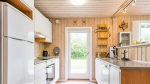 Une cuisine moderne avec un lambris en bois, des armoires blanches et un îlot central.