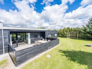Une maison moderne dotée d’un patio, d’un espace salon extérieur et d’une balançoire.