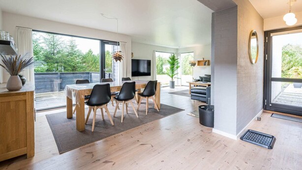 Una sala de estar moderna con comedor, ventanas amplias y un televisor de pantalla plana.