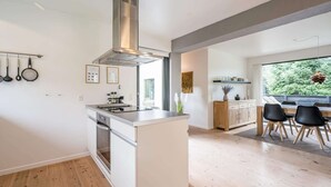 Una cocina moderna con una isla, suelo de madera y un comedor con vistas.