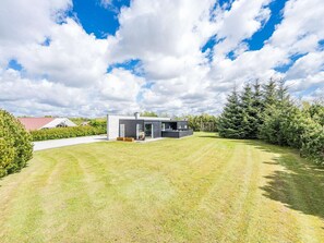 A modern house with a large lawn, a garage, and a well-maintained garden.