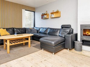 Un salon moderne avec un canapé d’angle, une table basse en bois et une cheminée.
