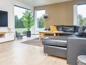 A modern living room with a leather sofa, a wooden coffee table, and a large potted plant.