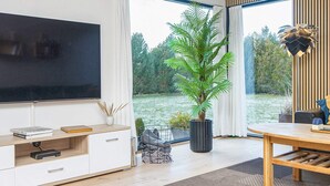 Una sala de estar moderna con un televisor de pantalla plana, una mesa de comedor de madera y una planta grande en maceta.