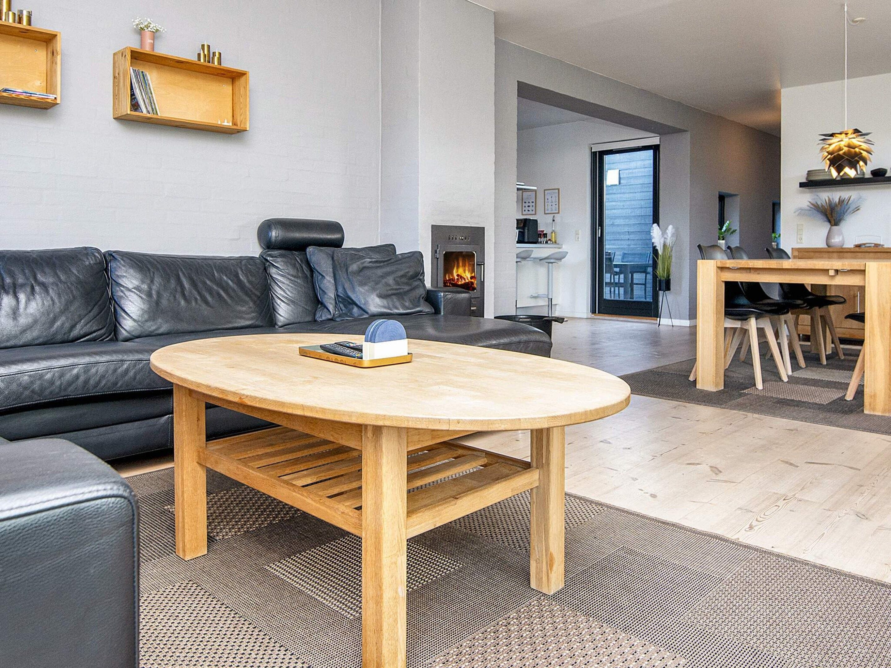 A modern living room with a leather sofa, a wooden coffee table, and a fireplace.