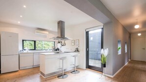 Una cocina moderna con una isla central, taburetes de bar y un ventanal grande.
