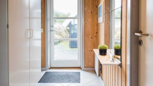 A wooden interior with a door leading outside, a small counter with plants, and a tiled floor. - 4 Star Holiday Home in Henne (Henne)