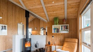 A cozy room with a wood-paneled interior, a fireplace, a leather armchair, and a bookshelf. - 4 Star Holiday Home in Henne (Henne)