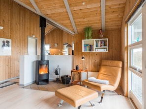 Een knus interieur met houten lambrisering, een open haard, een leren fauteuil en een boekenplank.