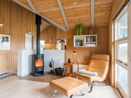 A cozy room with a wood-paneled interior, a fireplace, a leather armchair, and a bookshelf.