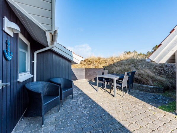 A patio with outdoor furniture, a window, and a view of the landscape.