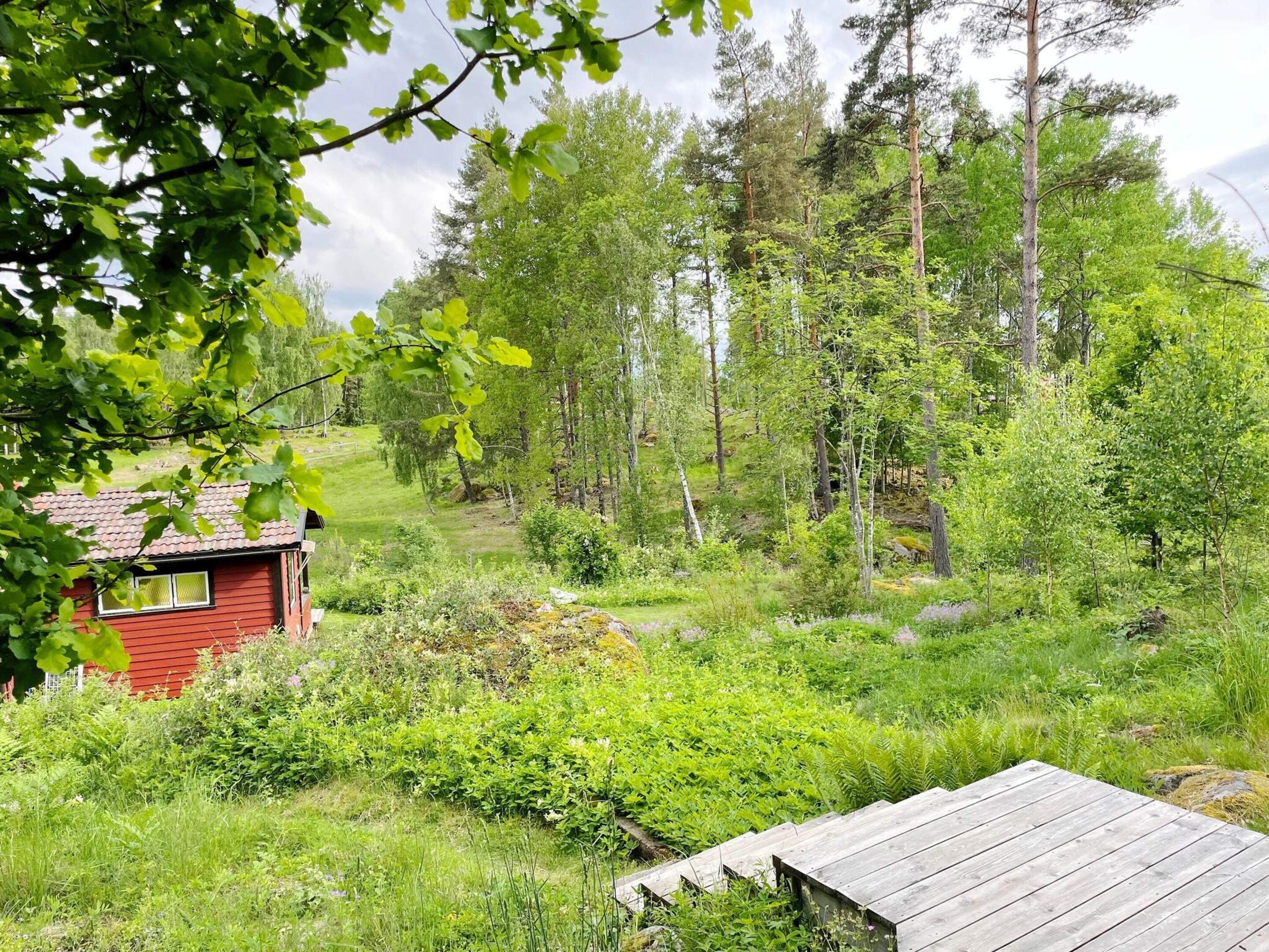 A red cabin with a view of a forested area.